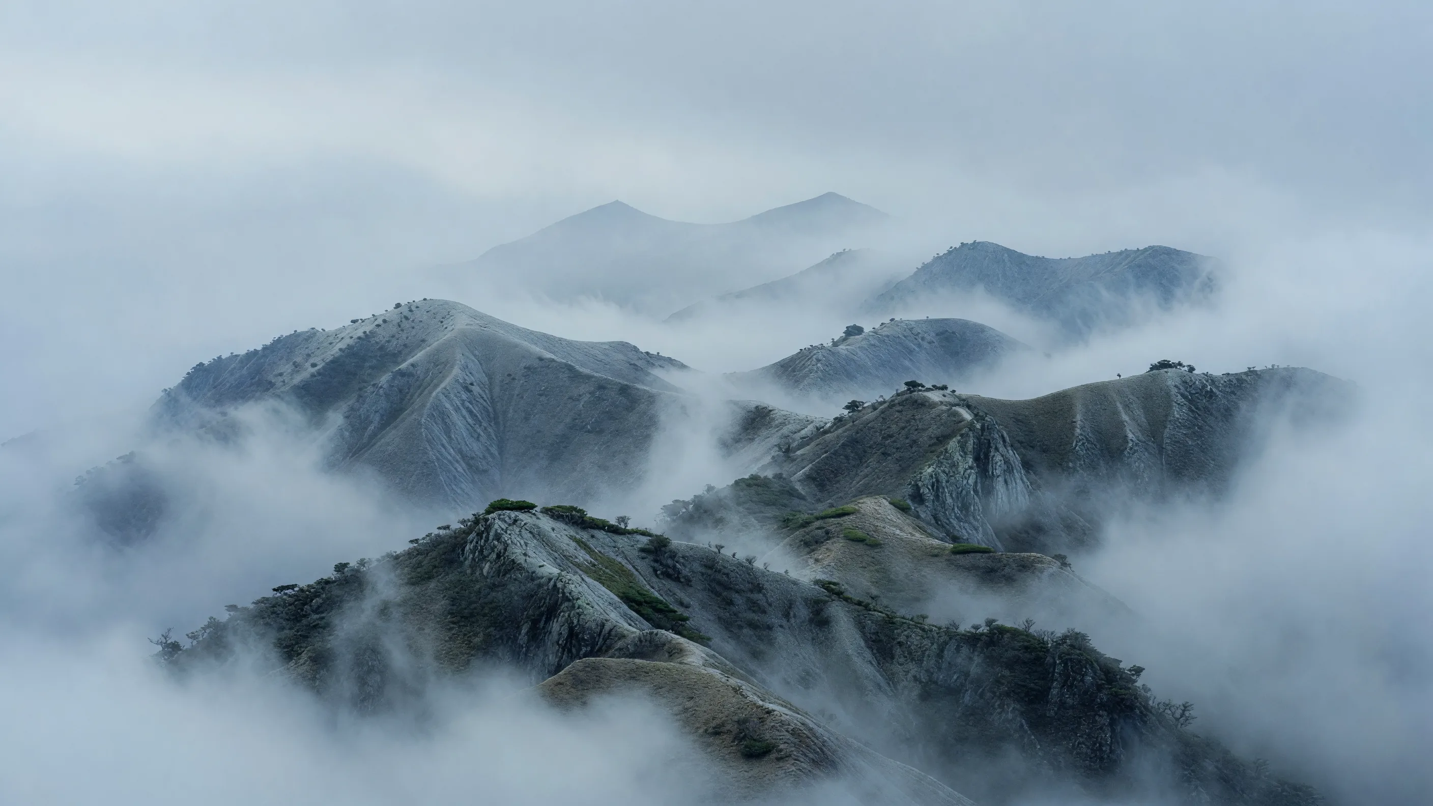 低い雲がかかる冬の重なる尾根